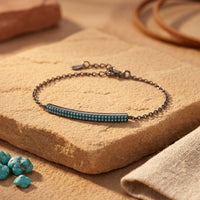 Sterling silver Escalante bracelet with a turquoise-set bar resting on a natural stone in a Southwestern setting.