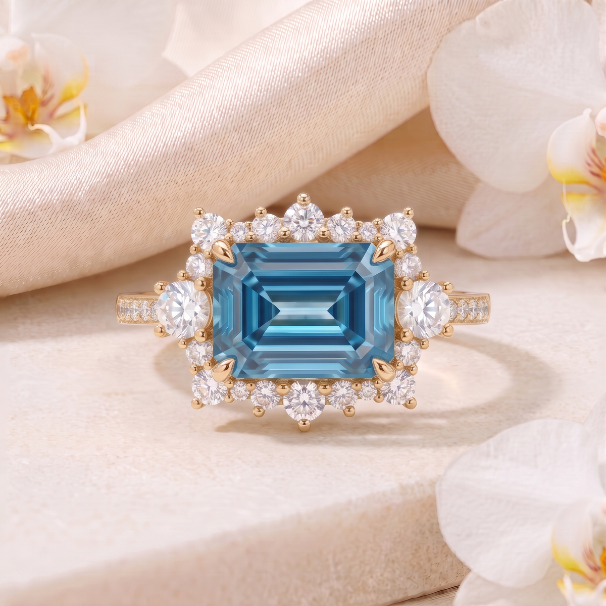 Front view of an emerald-cut blue moissanite halo ring in yellow gold on a stone surface.