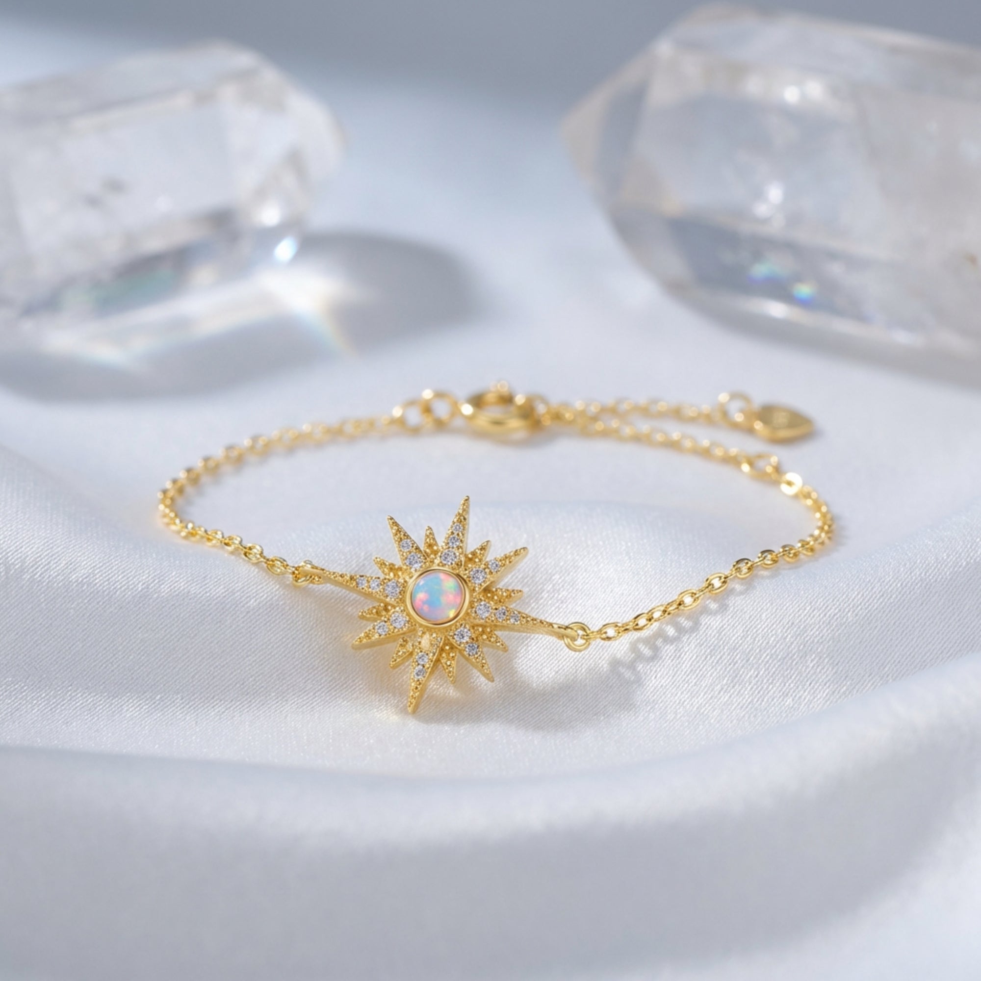 Elowen starburst bracelet in gold-tone sterling silver with a round-cut white opal on white silk fabric.