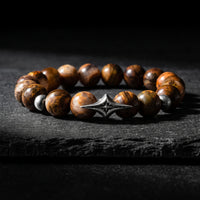 North Star beaded bracelet with brown gemstone beads and a silver four-pointed star station on dark slate