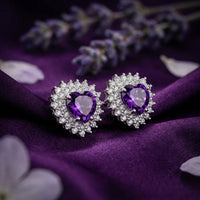 Heart cut amethyst earrings in sterling silver with a halo, styled on purple silk with lavender sprigs.