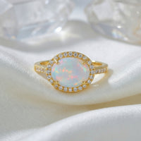 Front view of the gold vermeil Magnolia statement ring with an oval cut natural opal on white silk.