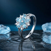 Floral aquamarine ring in sterling silver on a wet stone surface with blue lighting and ice crystals.