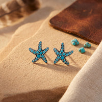 Sterling silver starfish stud earrings with round turquoise stones on a desert-themed stone background.