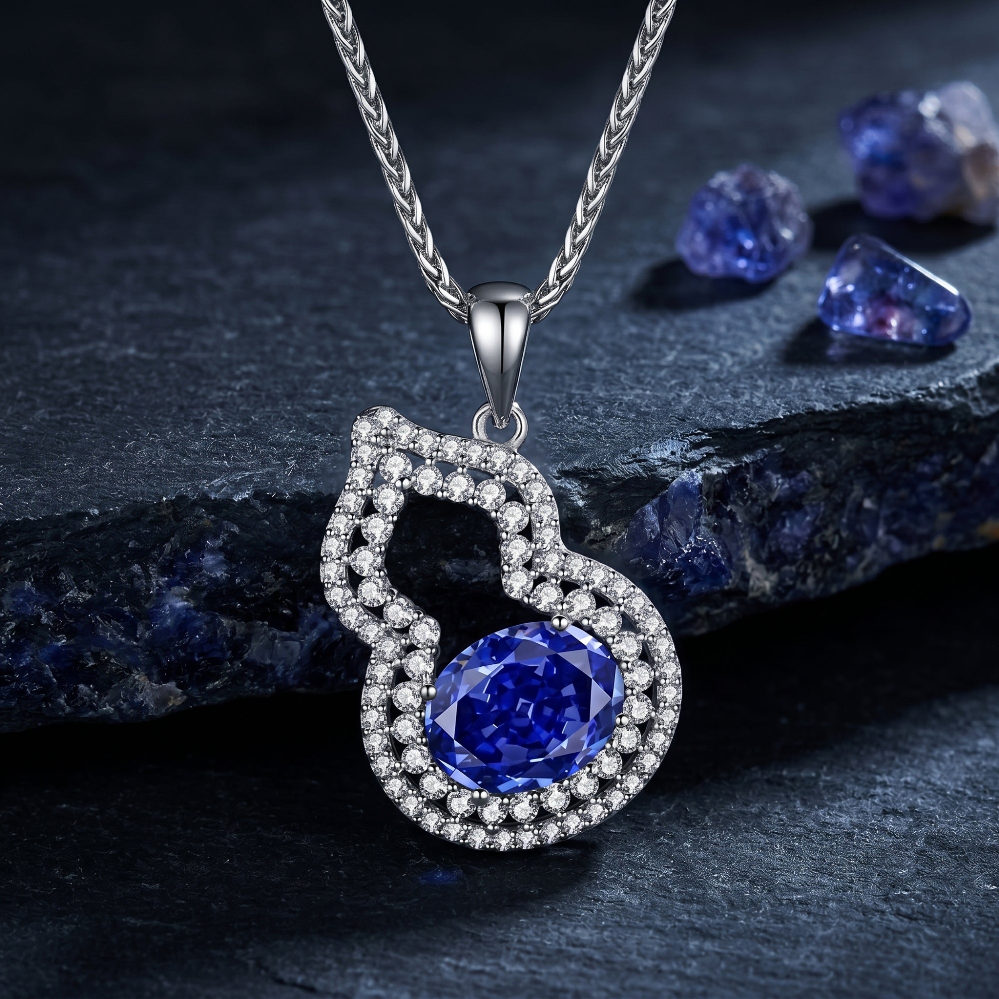 Oval natural tanzanite halo pendant in white gold on a dark stone background with raw gemstones.