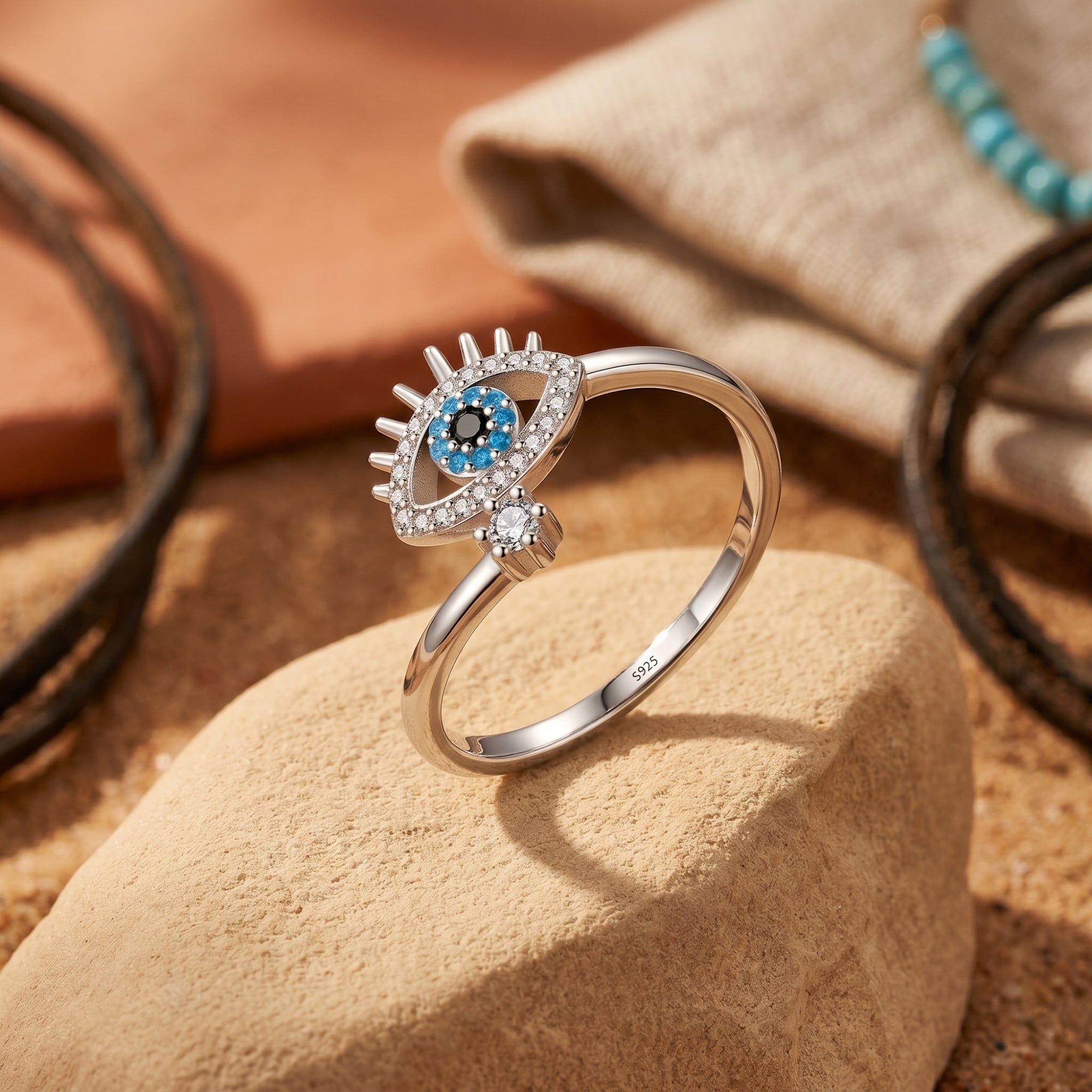 Silver Amaya evil eye ring with a turquoise cabochon and white stones, styled on a desert rock.