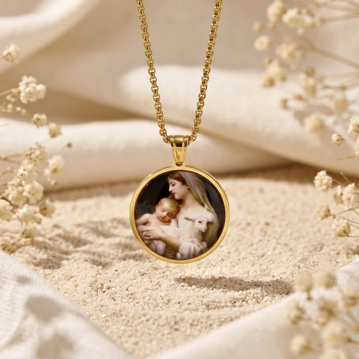 Gold-tone round medallion necklace with a Madonna and Child portrait, suspended against sandy backdrop.