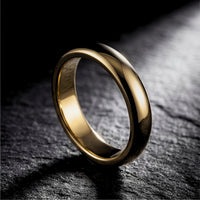 5mm gold tone stainless steel band ring standing on a dark, textured stone surface.