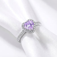 Angled top view of the heart-cut simulated amethyst halo ring in S925 sterling silver on white draped fabric.
