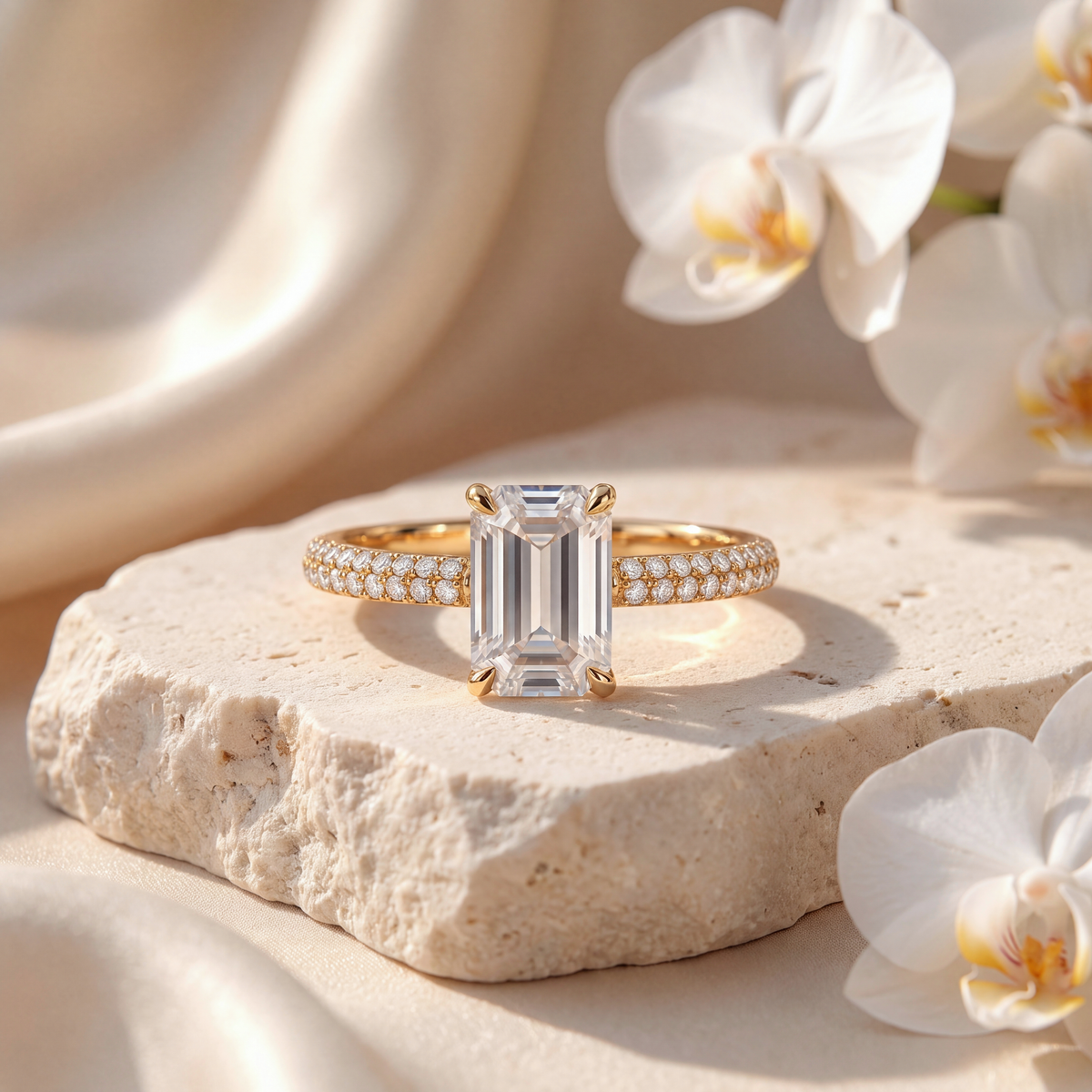 Gold emerald-cut moissanite engagement ring with double-row pavé band displayed on stone.