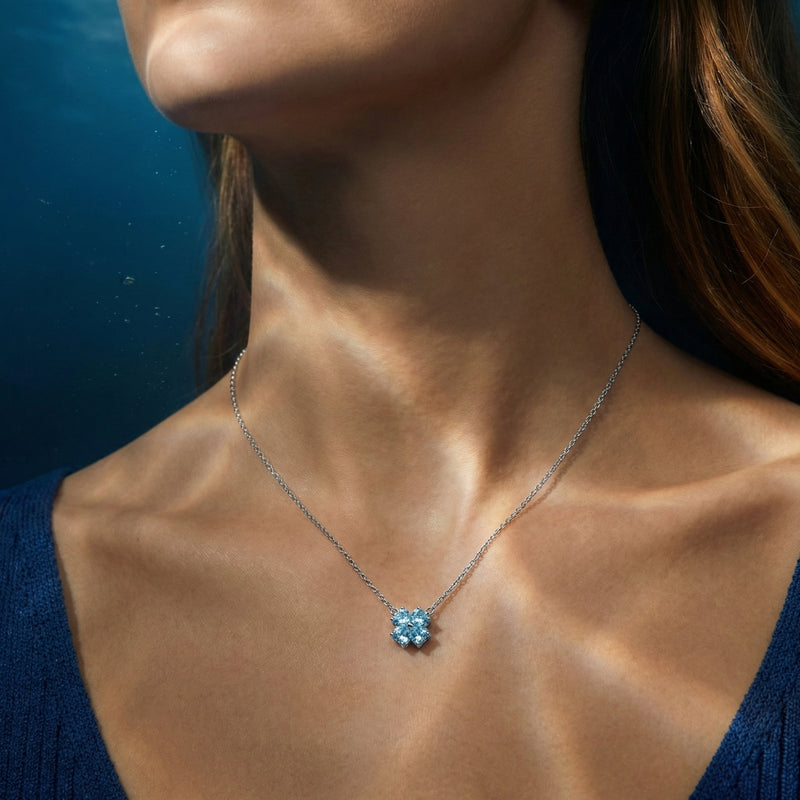 Model wearing the platinum Marina clover necklace featuring four heart-cut light blue aquamarine stones.