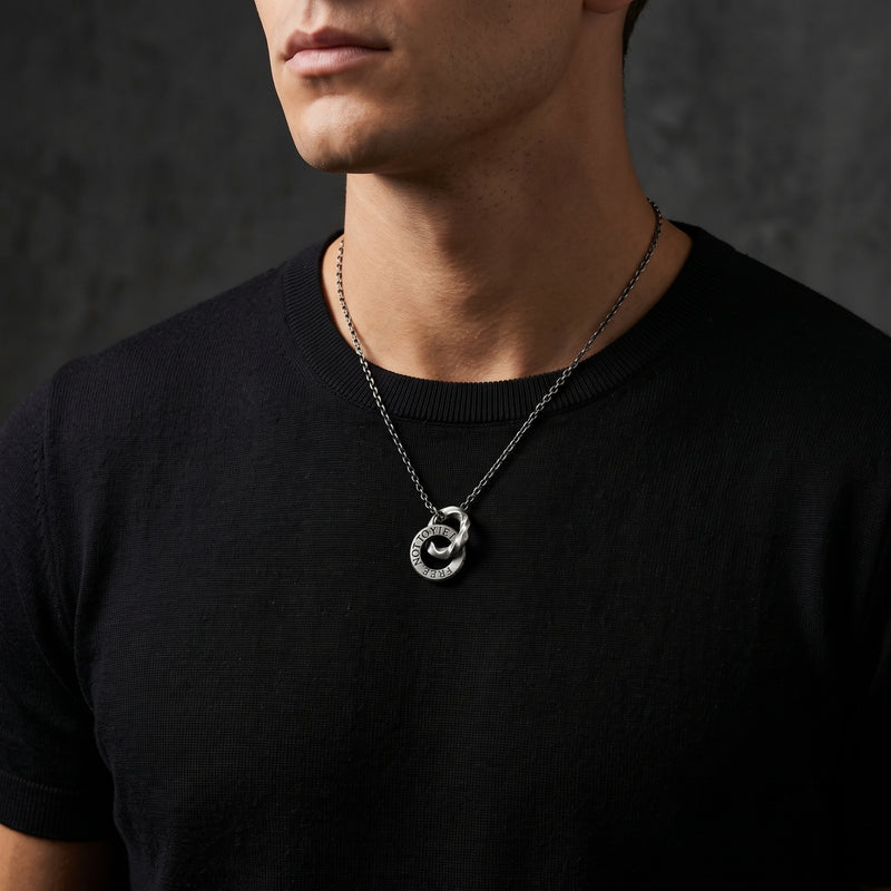 Clean-shaven model wearing the silver inscribed dual-ring pendant over a black crewneck top.