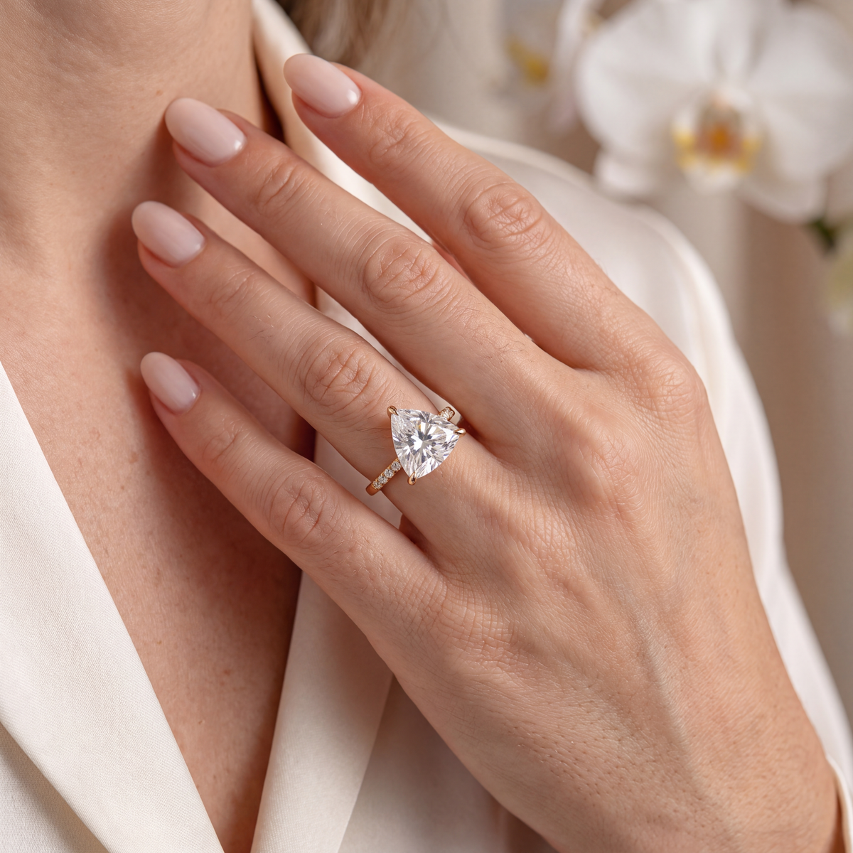 Yellow gold trillion-cut moissanite engagement ring styled on a model's hand.