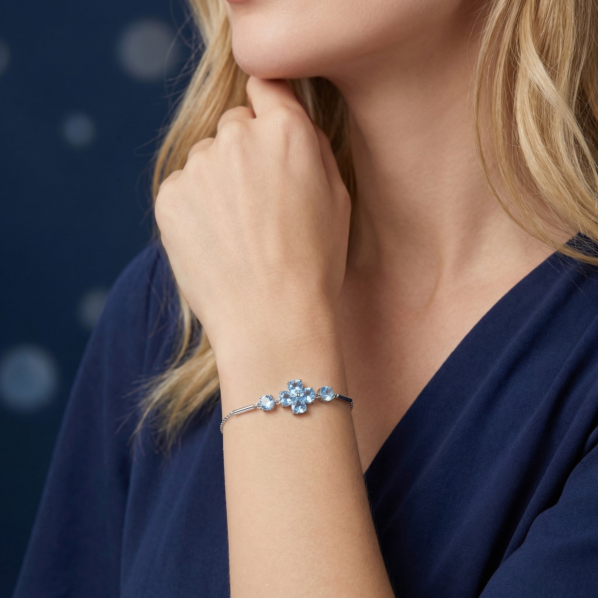 Woman wearing the silver Azurette clover bracelet with heart and round cut Swiss blue topaz stones on her wrist.