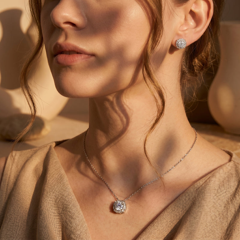 Woman wearing the Aurestella round-cut moissanite halo pendant necklace and matching silver stud earrings.