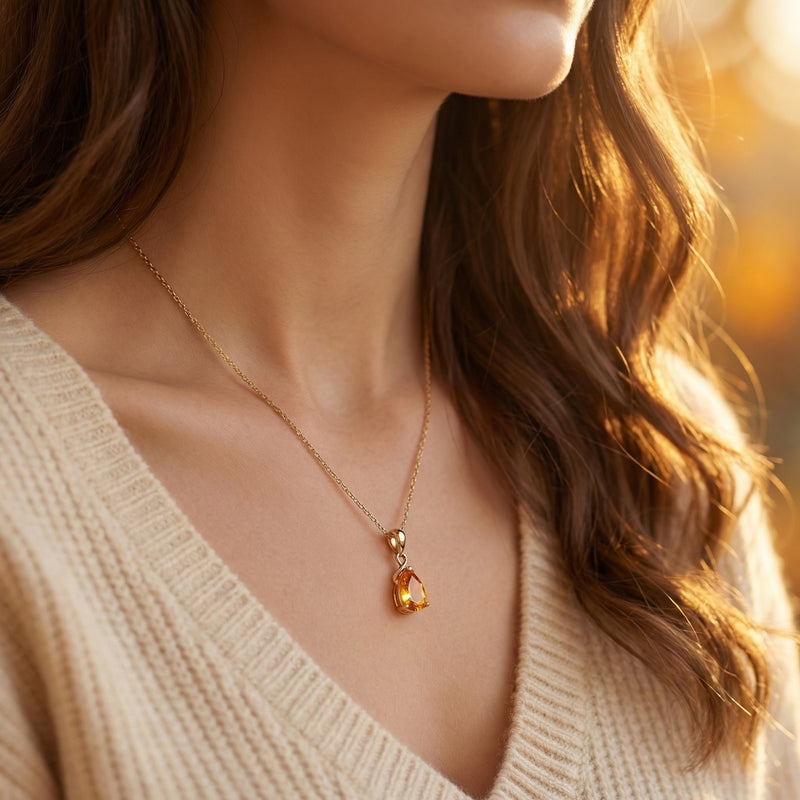 Woman wearing the 18K yellow gold pear cut citrine necklace over a cream knit sweater.