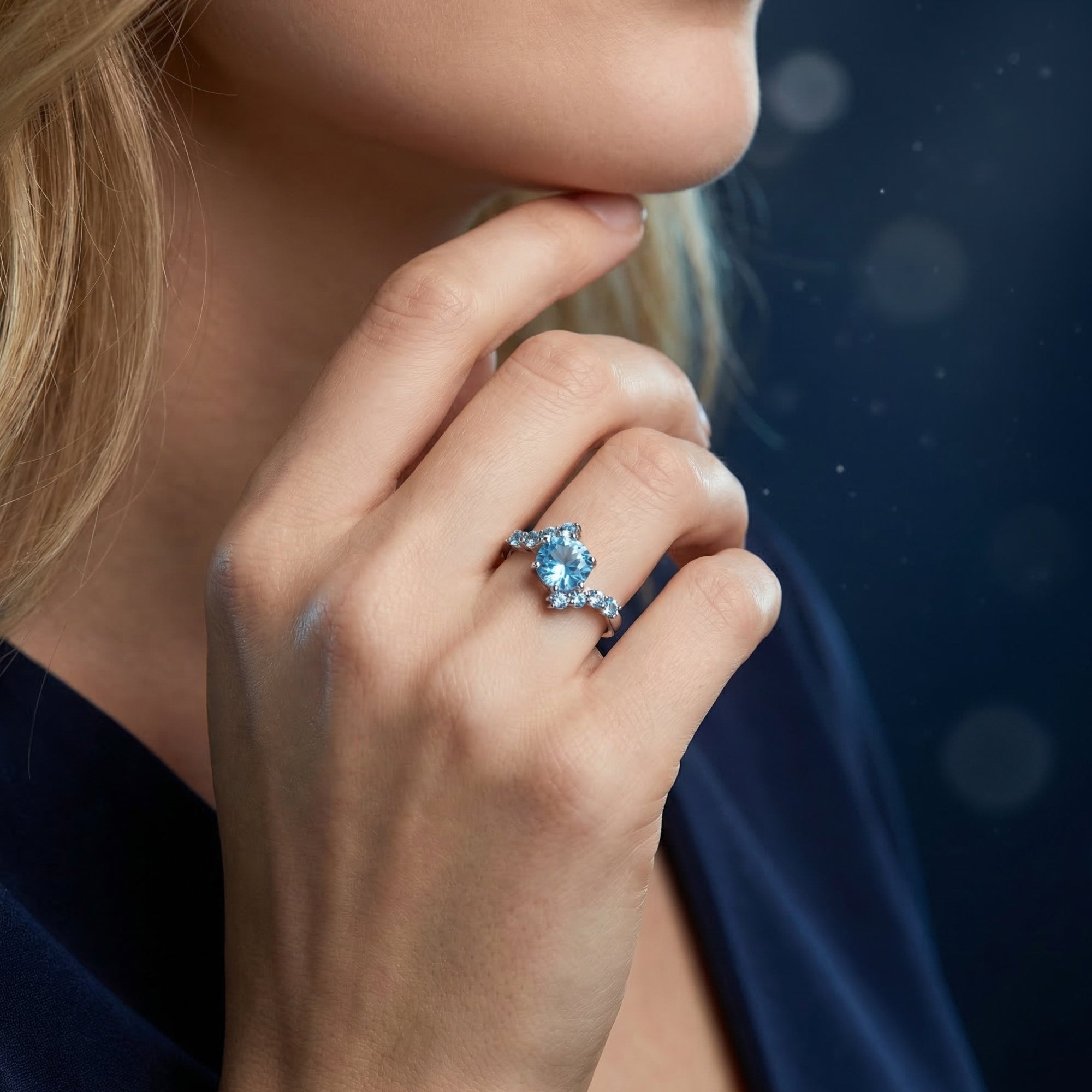 Woman wearing the Lydienne natural blue topaz round cut ring in sterling silver on her finger.
