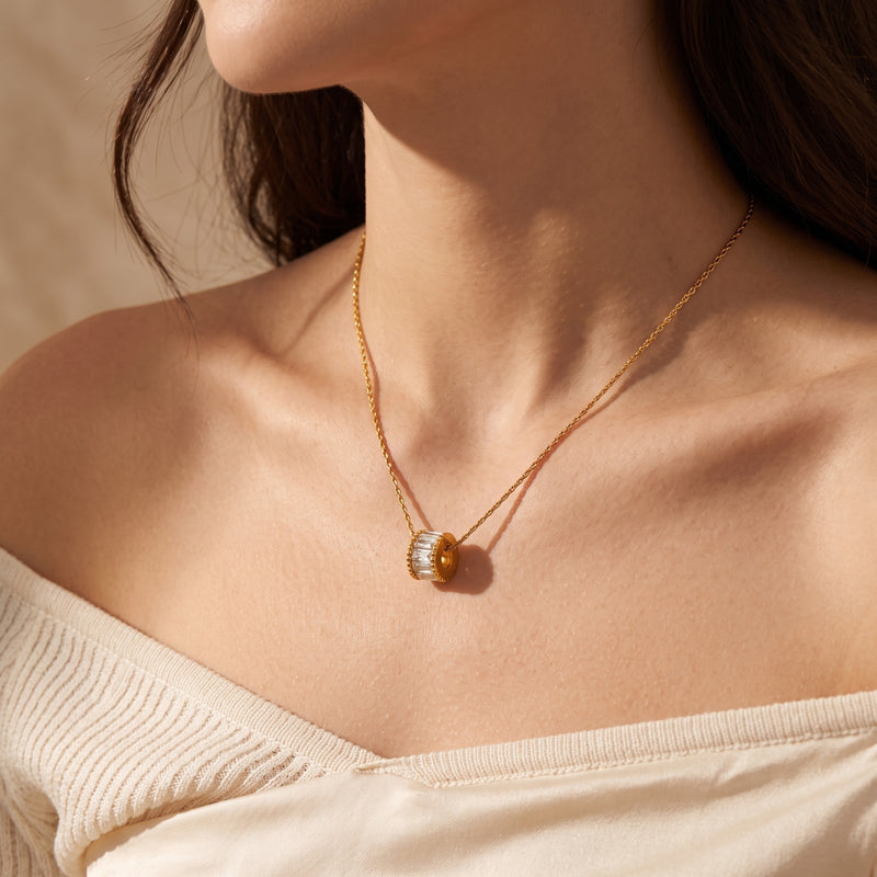 Woman wearing the gold Elyndelle necklace with a baguette-cut stone wheel pendant.