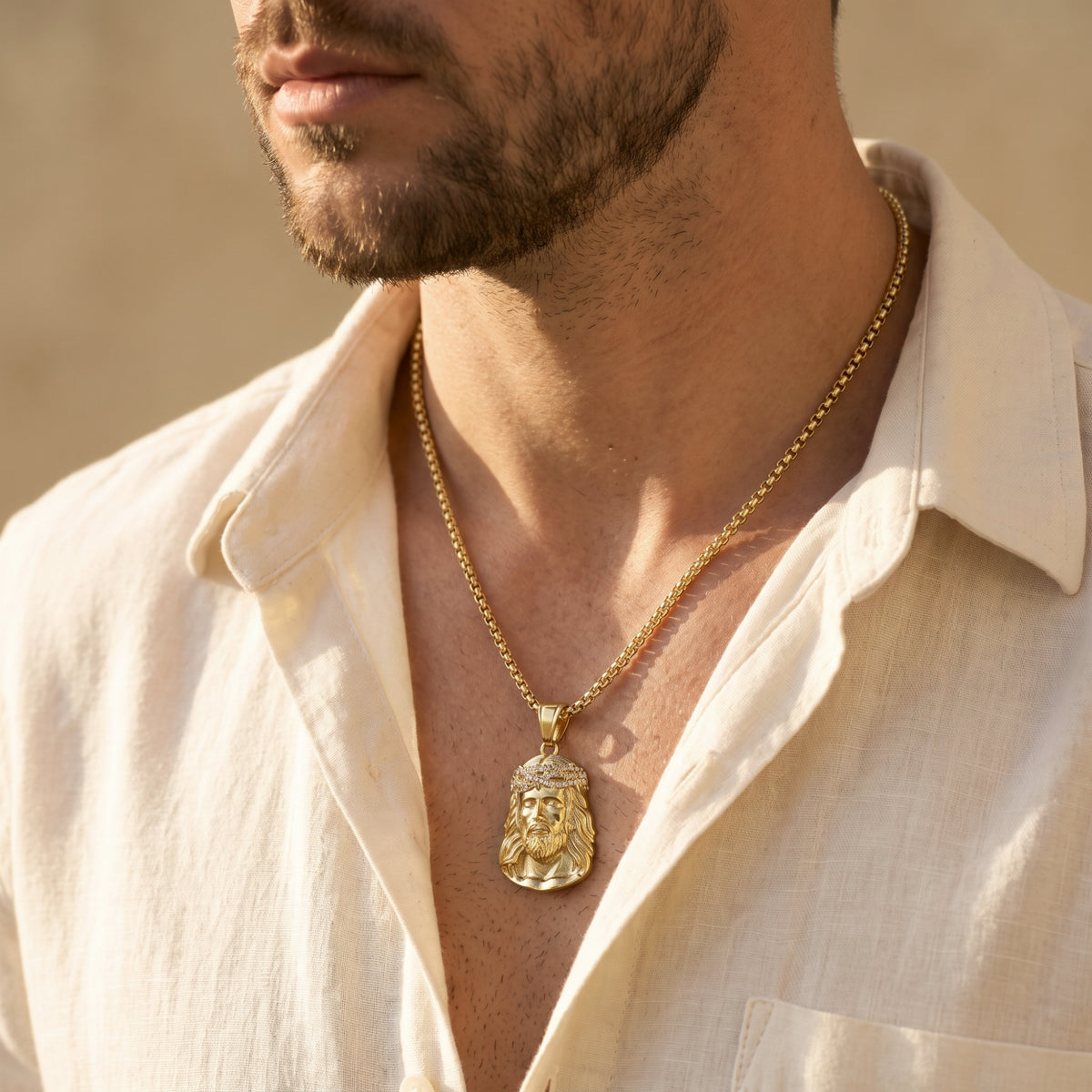 Side-profile view of a man wearing a gold-tone Jesus portrait pendant with an open white shirt.