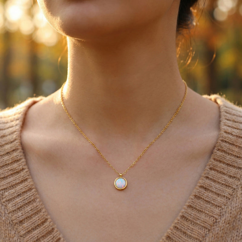 Model wearing the gold finish round cut white opal necklace against a warm outdoor background.