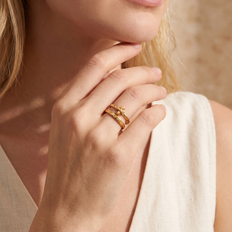 Close-up of a woman wearing the gold-tone double-band cross ring on her ring finger near her chin.