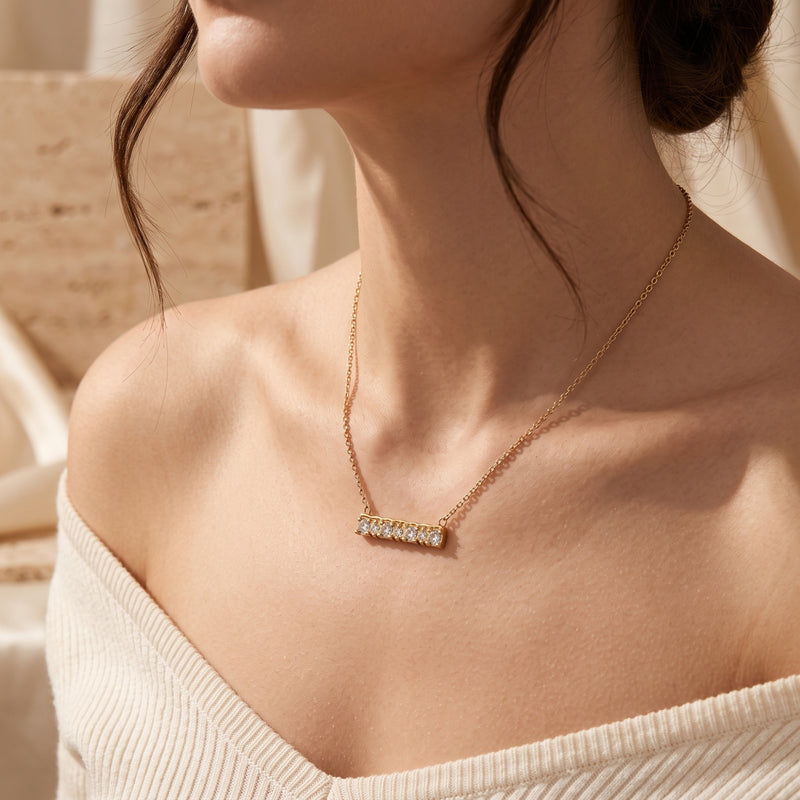 Model wearing the gold Aurendelle bar necklace with seven flush-set cubic zirconia stones.