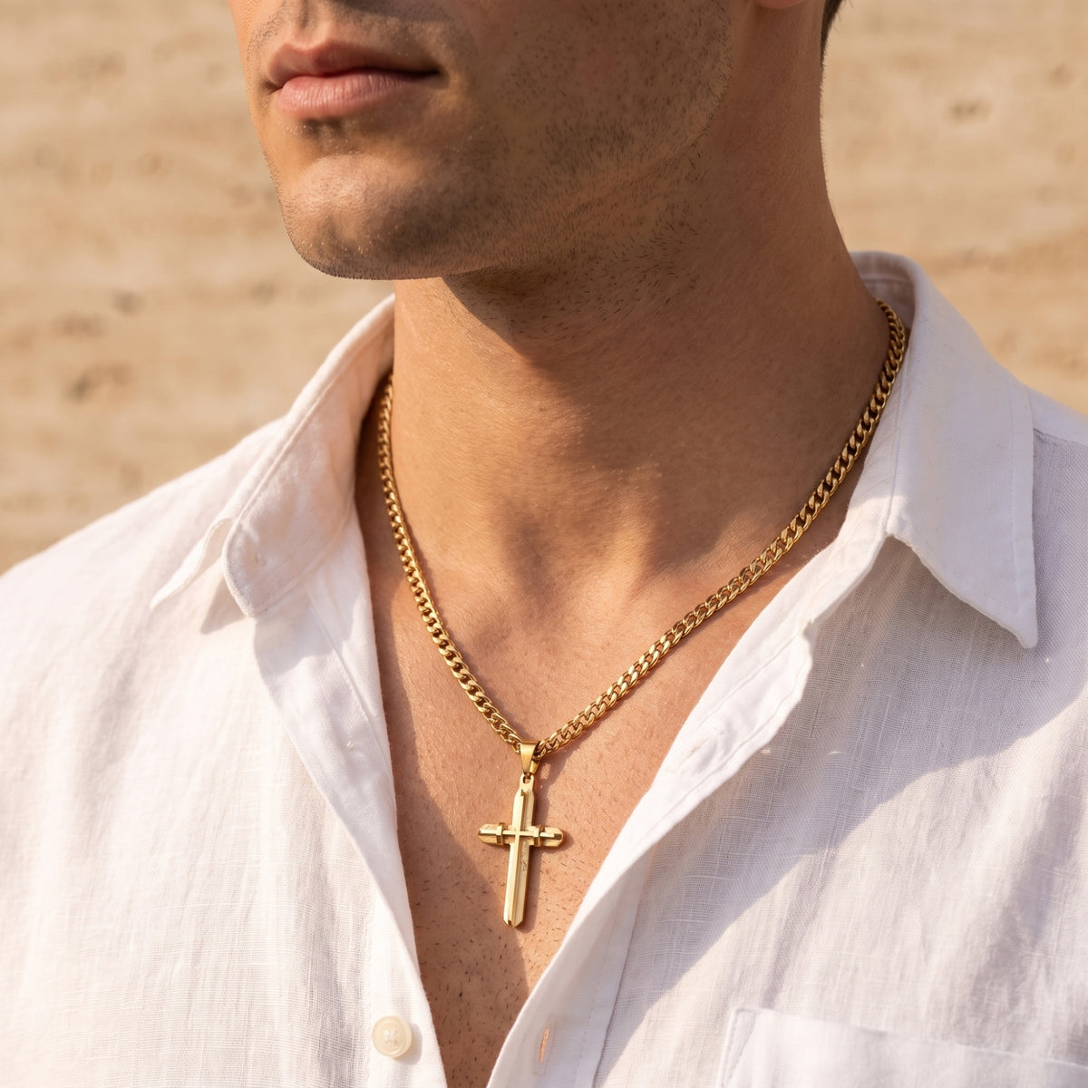 Gold-toned cross necklace worn by a model in an open white shirt, shown in left-facing profile.