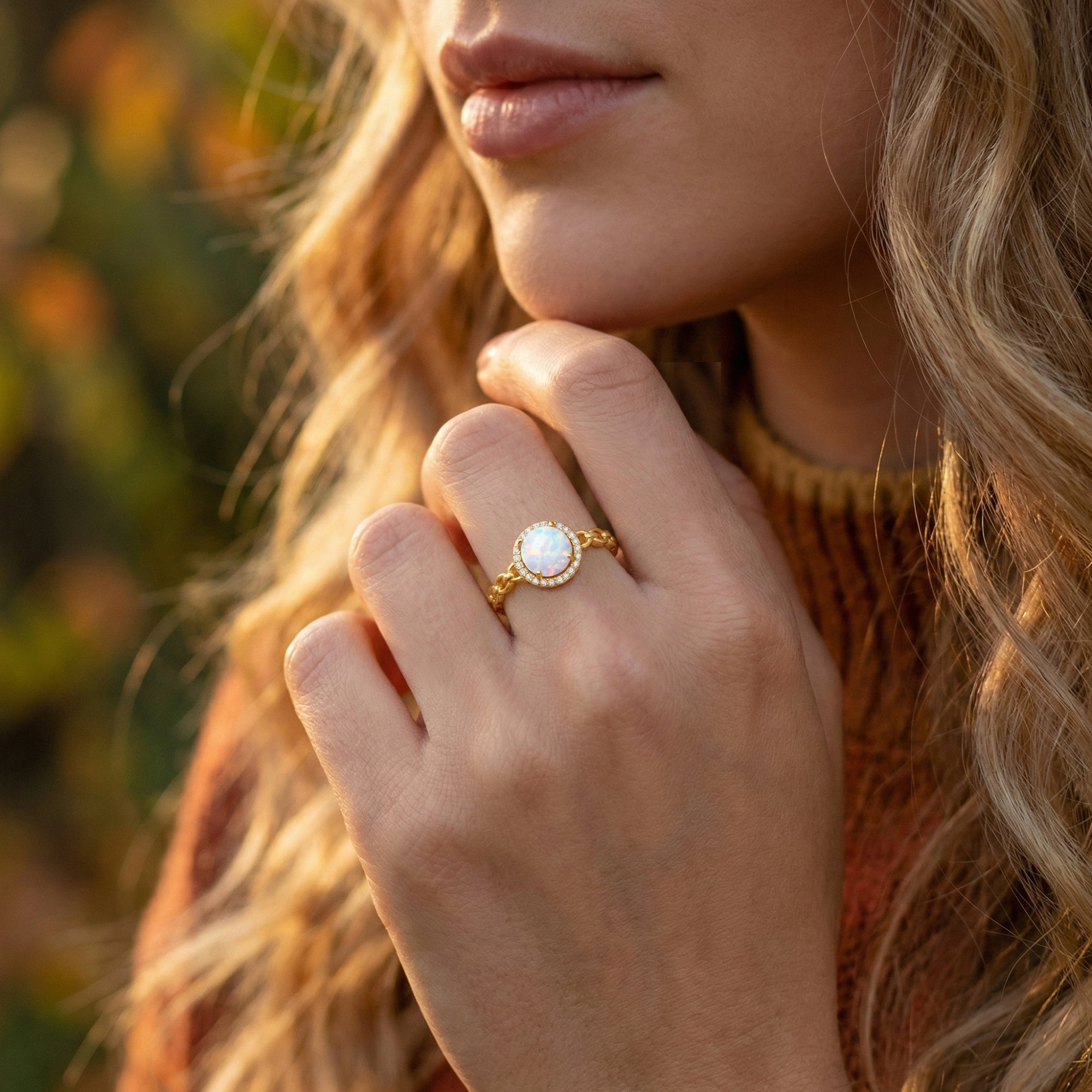Model wearing the gold-tone Aureoline white opal statement ring on her finger in a natural outdoor setting.