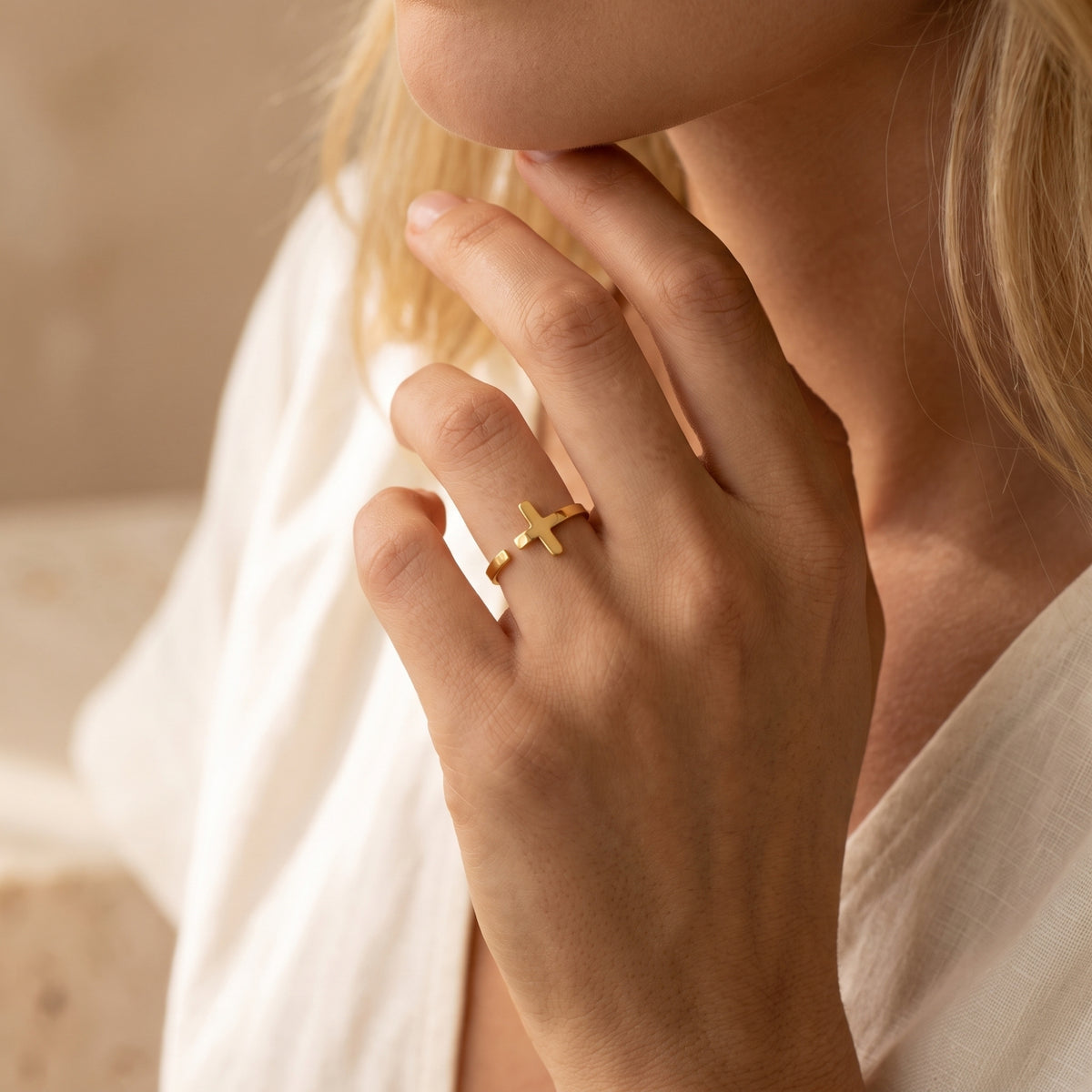 Model wearing the gold-tone cross open ring on her middle finger in a soft lifestyle view.