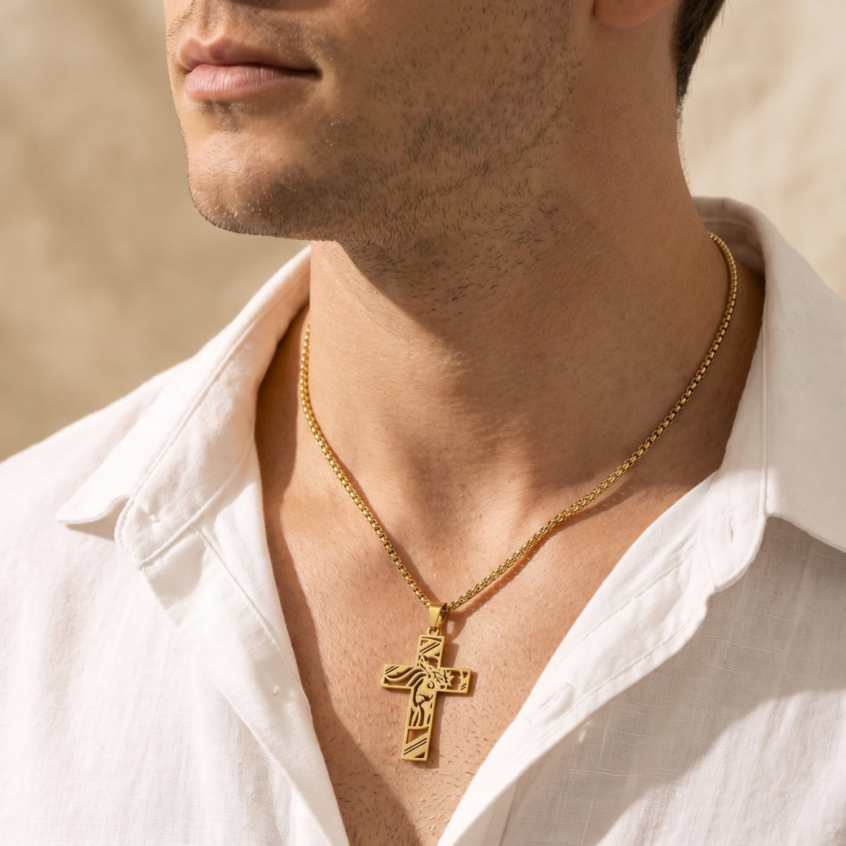 Front close-up of a man wearing a gold-tone cutout cross necklace with an open white shirt.