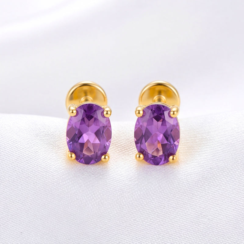 Pair of oval-cut simulated amethyst stud earrings in 18K gold vermeil shown on white fabric.