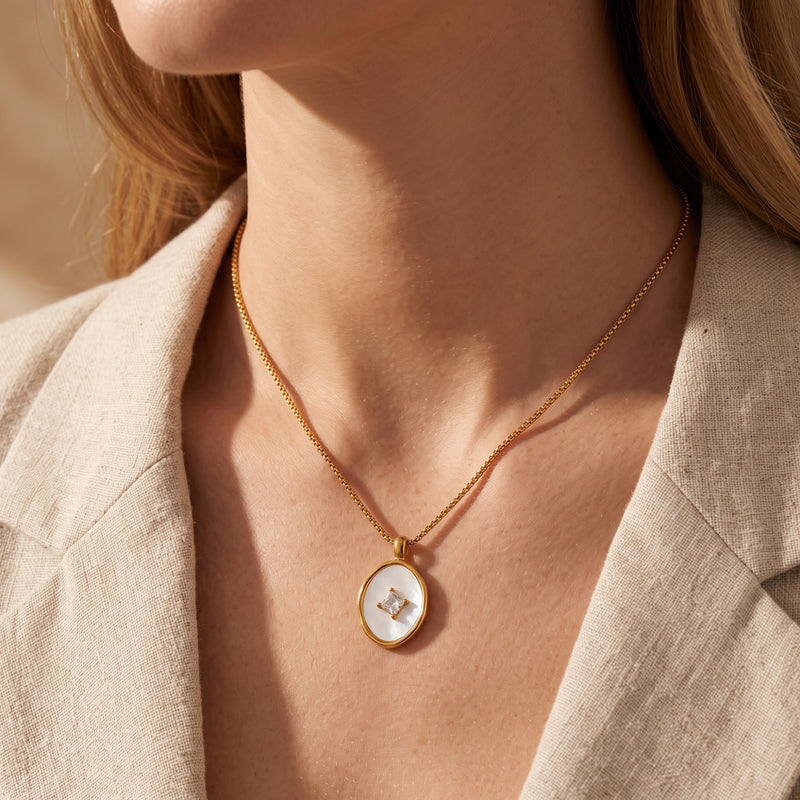 18K gold Lucelle pendant necklace with mother of pearl inlay styled on a model wearing a neutral-toned blazer.