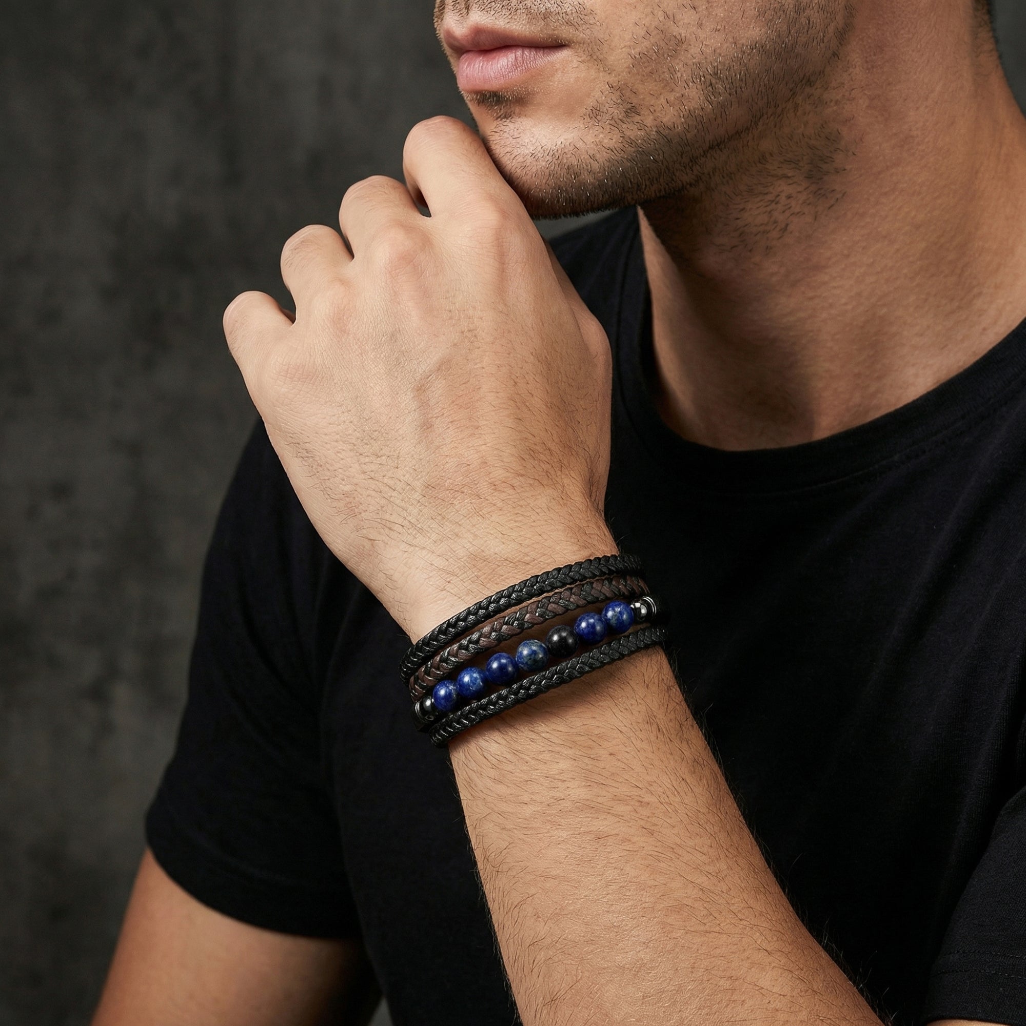Men's black braided leather bracelet with blue lapis lazuli beads worn on a wrist.