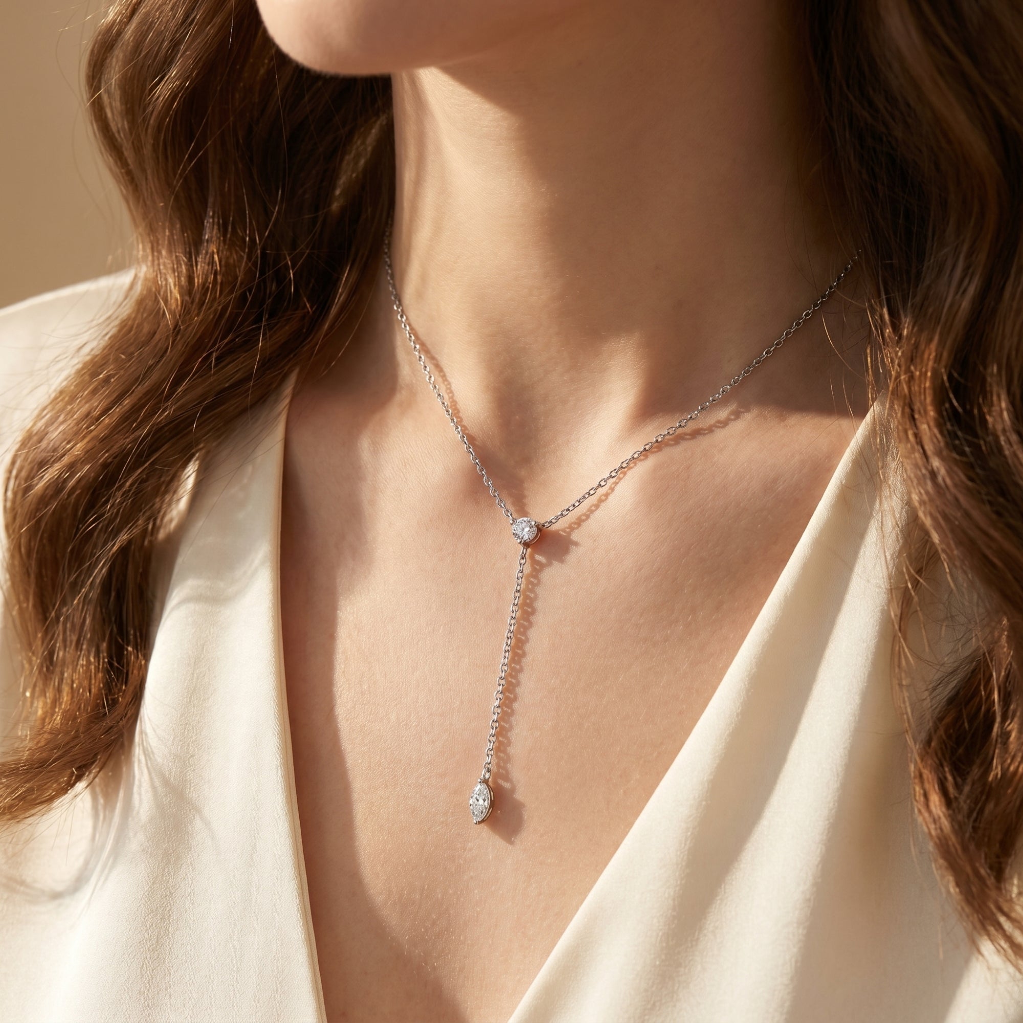 Woman wearing the silver Rosamel lariat necklace with round and marquise-cut moissanite stones.