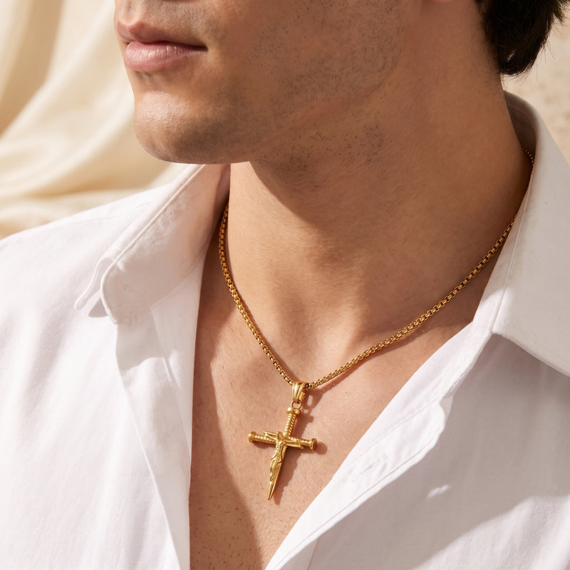 Close-up of a man wearing a gold-tone nail cross necklace with an open white shirt.