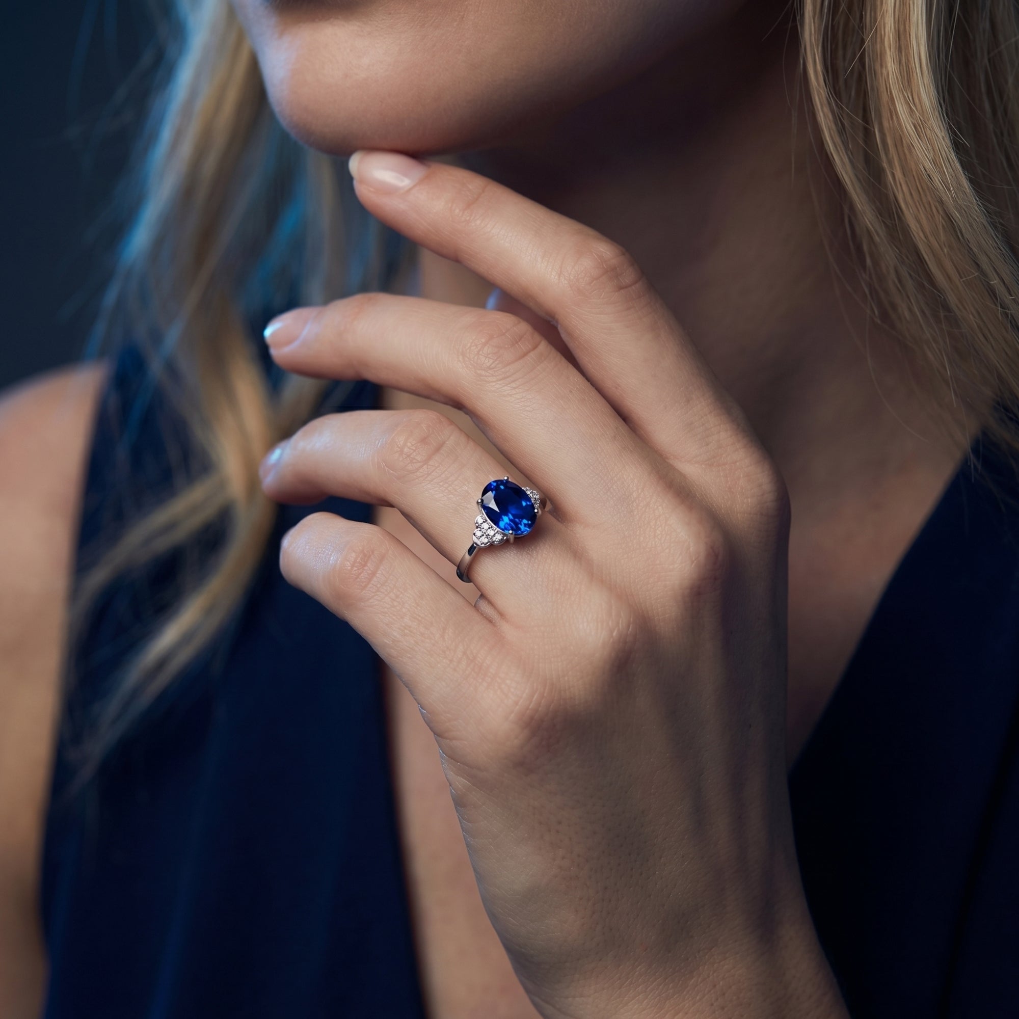 Model wearing the Kaelani oval tanzanite and diamond ring in 18K white gold, resting her hand on her chin.
