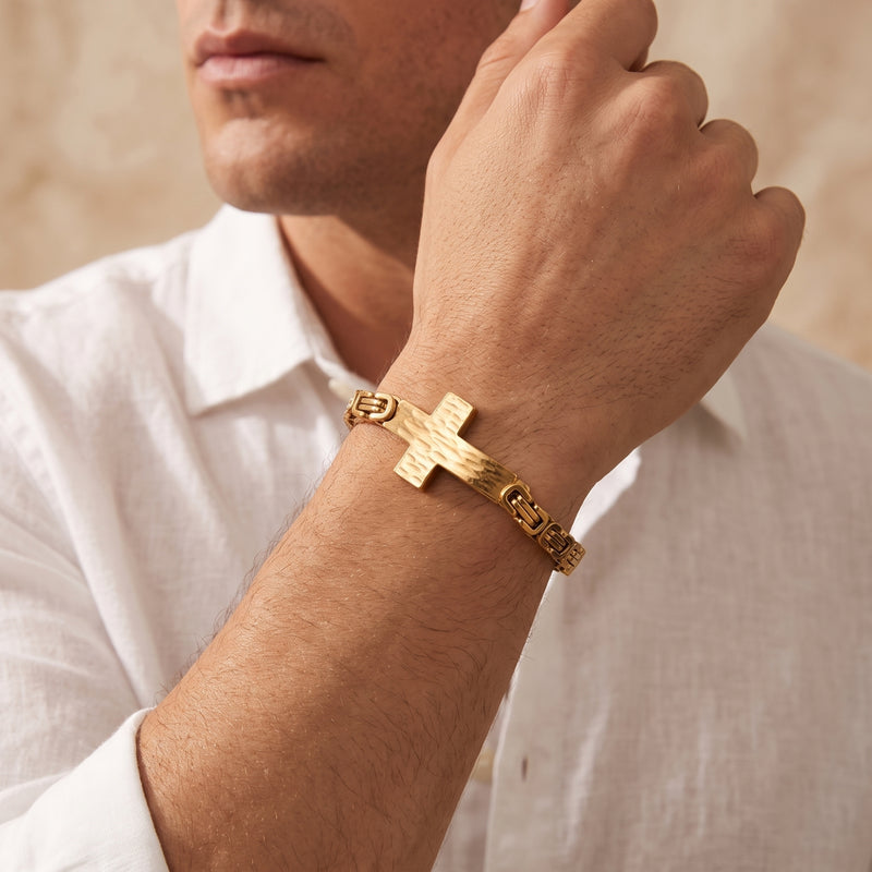 Close-up of a man wearing the gold-tone hammered cross Byzantine bracelet on his wrist.