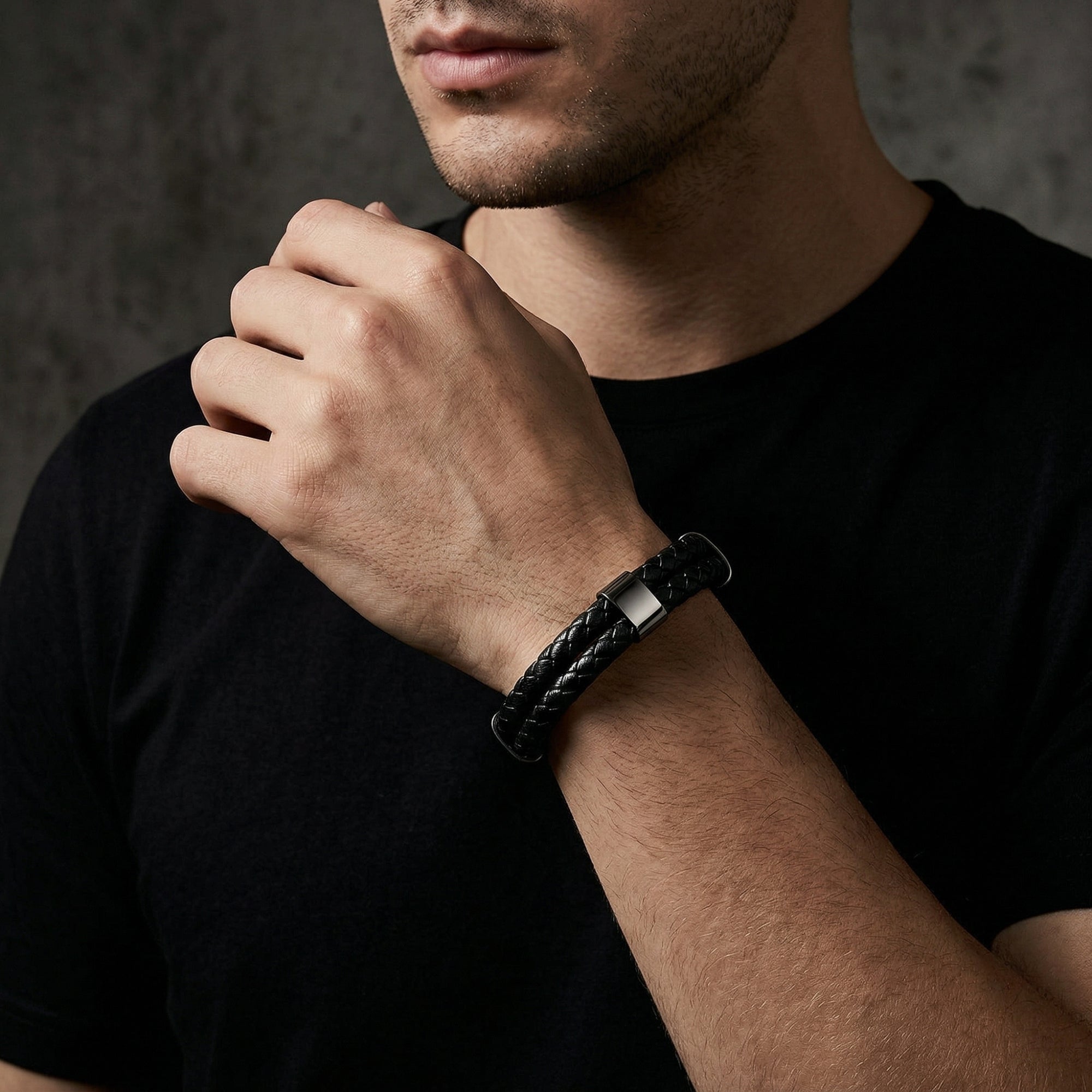 Men's double-braided black leather bracelet with black stainless steel clasp worn on a wrist.