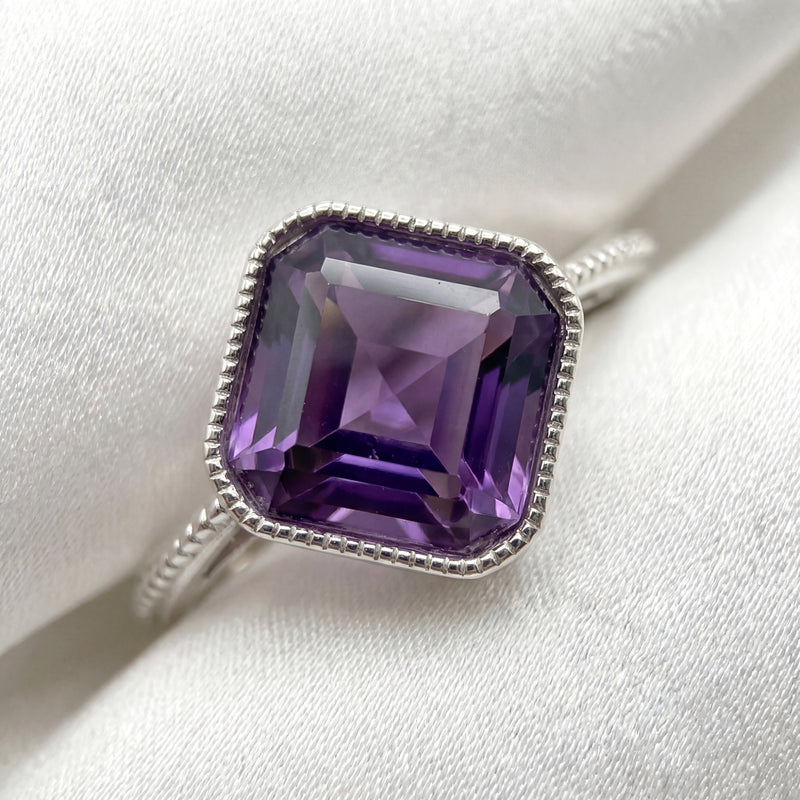 Macro detail of the 8mm cushion-cut simulated amethyst and textured S925 sterling silver bezel.