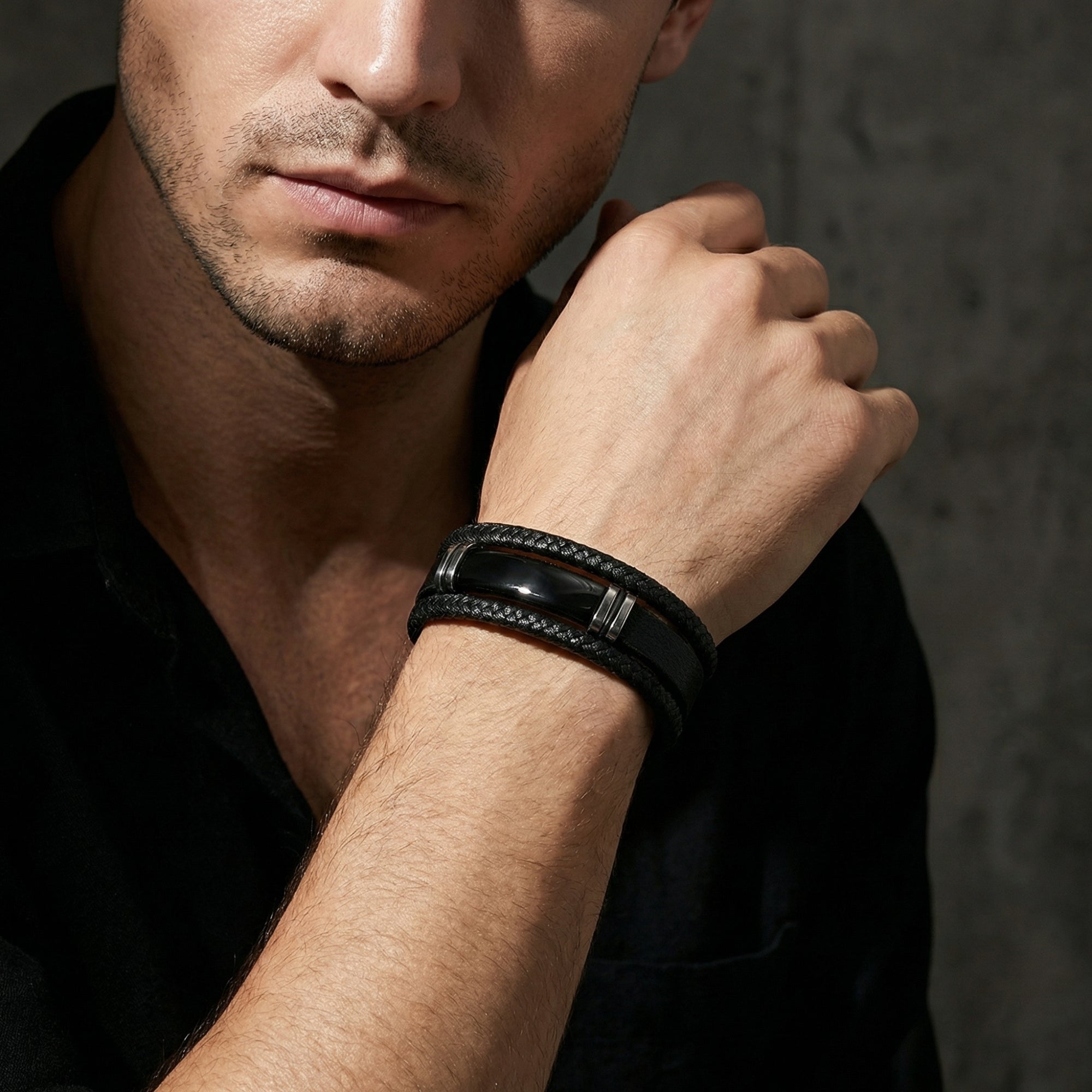Men's black braided leather bracelet with a black stainless steel clasp worn on a model's wrist.