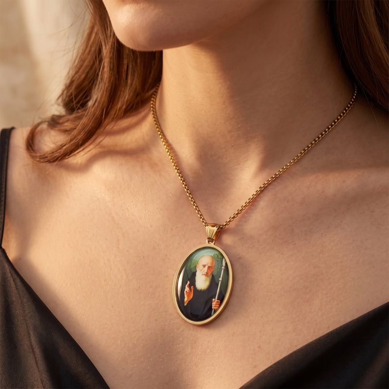 Gold-tone saint medallion necklace worn on a woman's neck above a black top.