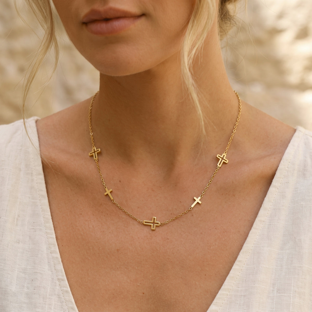 Front neckline view of a model wearing the gold-tone multi-cross necklace with a white top.