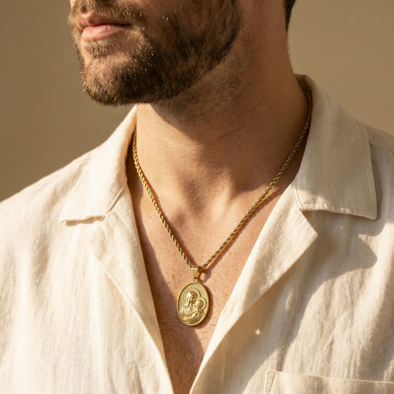 Gold-tone Madonna medallion necklace worn on a man in a cream linen shirt.