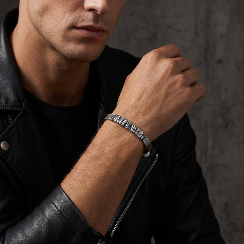 Silver sculpted segment cuff bracelet on a man's wrist, paired with a black leather jacket.