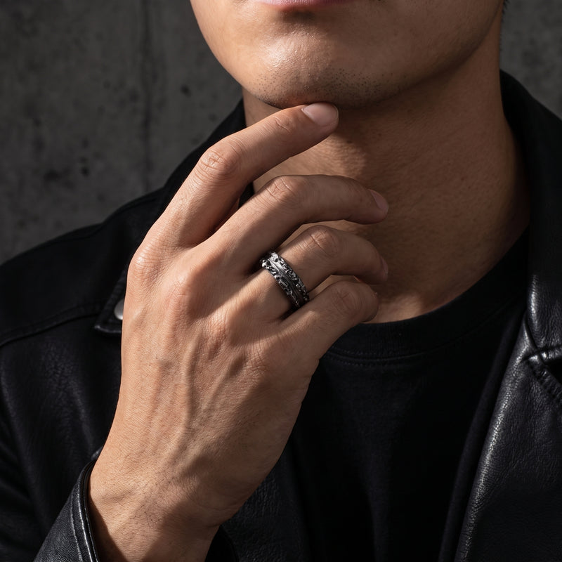 Close-up of a man wearing a textured silver ring while resting his hand against his chin.