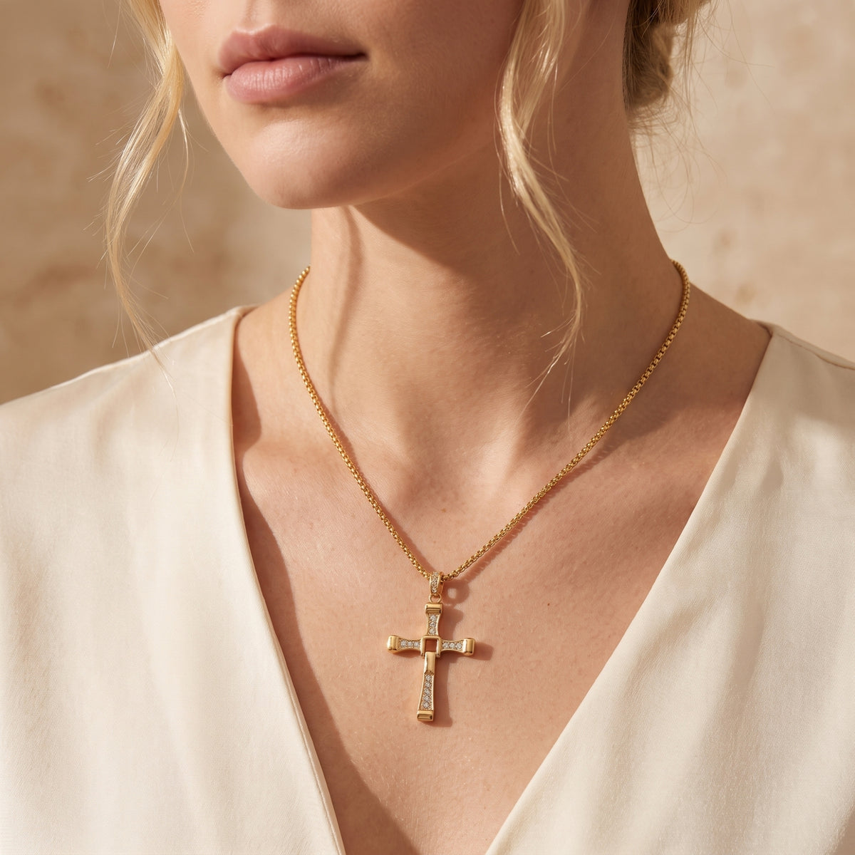 Model wearing a gold-tone crystal-studded hinged cross necklace with a cream V-neck blouse.