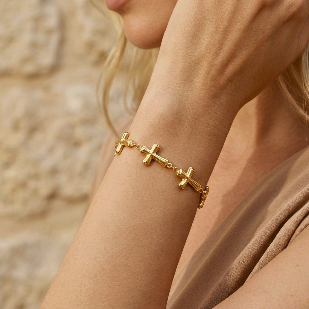 On-model view of the gold-tone cross station bracelet worn on a wrist against a neutral background.