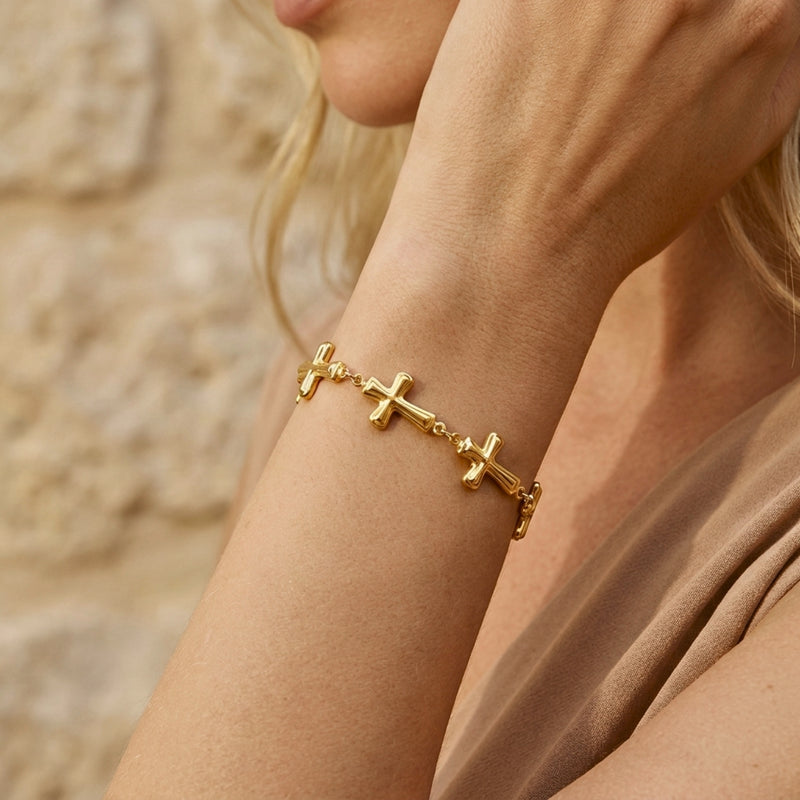 On-model view of the gold-tone cross station bracelet worn on a wrist against a neutral background.