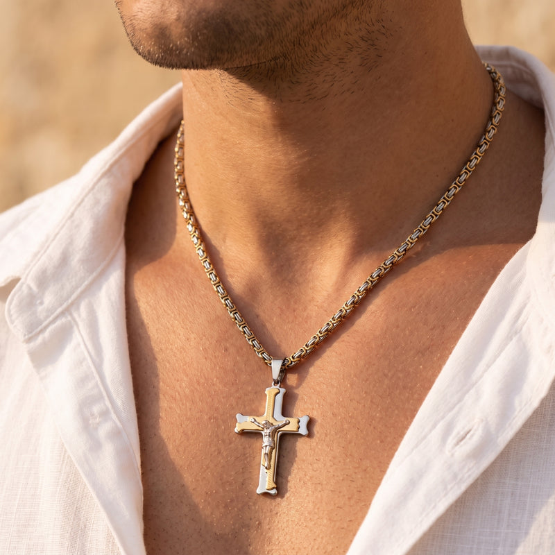Close-up of a man's neck and chest wearing a two-tone crucifix pendant on a Byzantine chain.