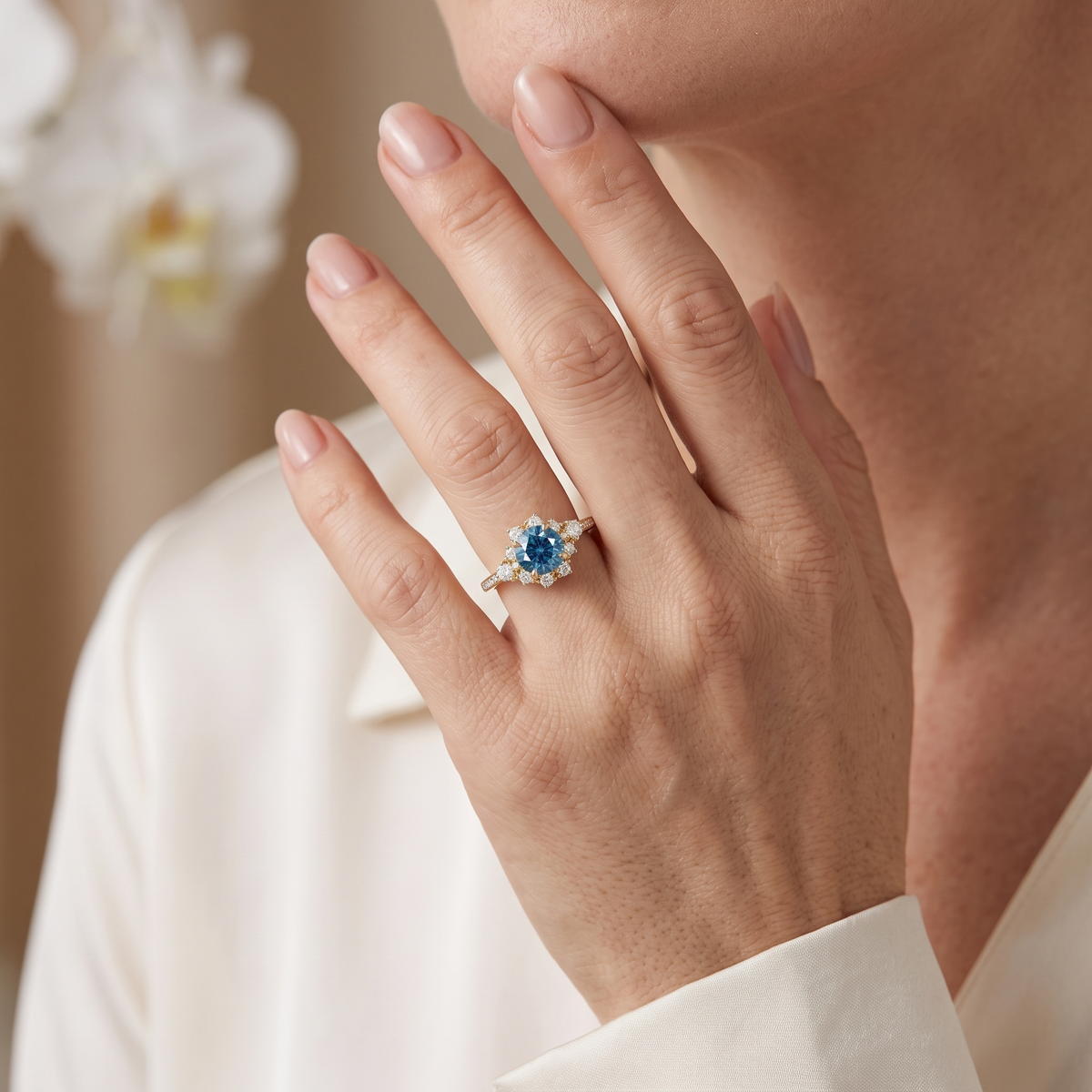 Model wearing a yellow gold round blue moissanite halo ring on her finger.
